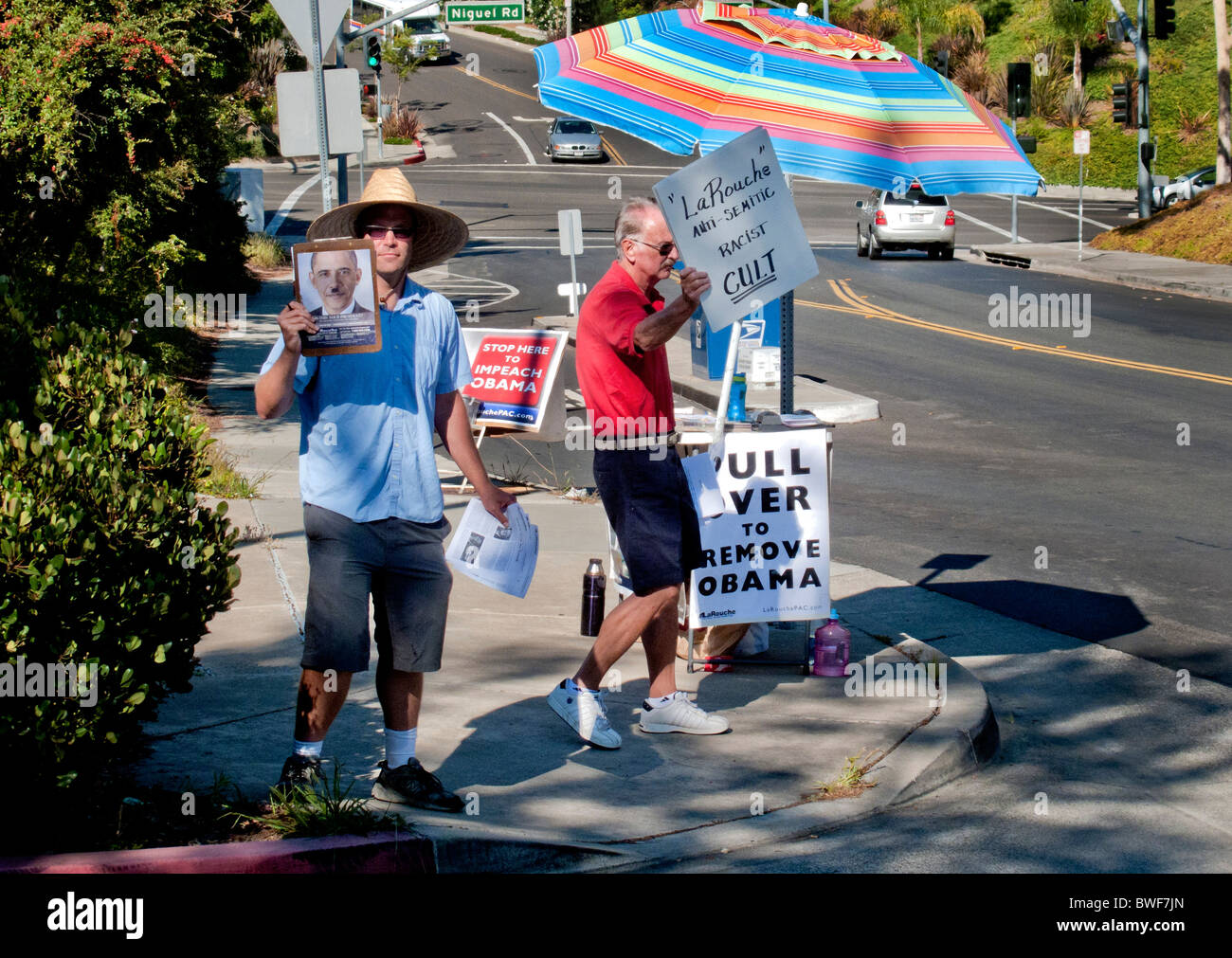 Activist seeks the impeachment of US President Obama while a counter demonstrator has sign denouncing activist's organization. Stock Photo
