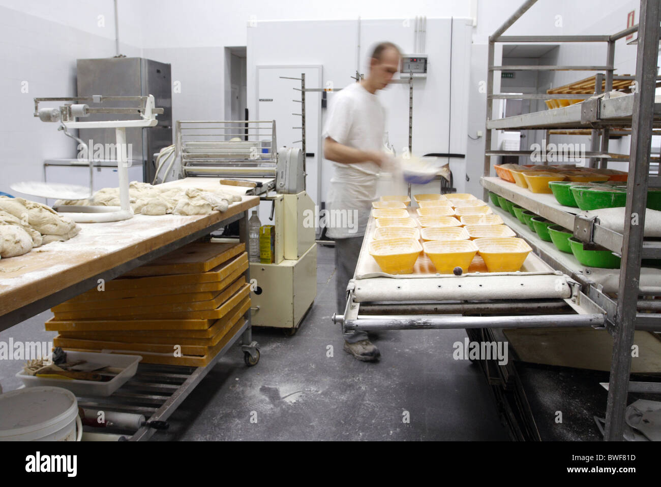 A baker distributing flour into plastic bread molds, Conil de la
