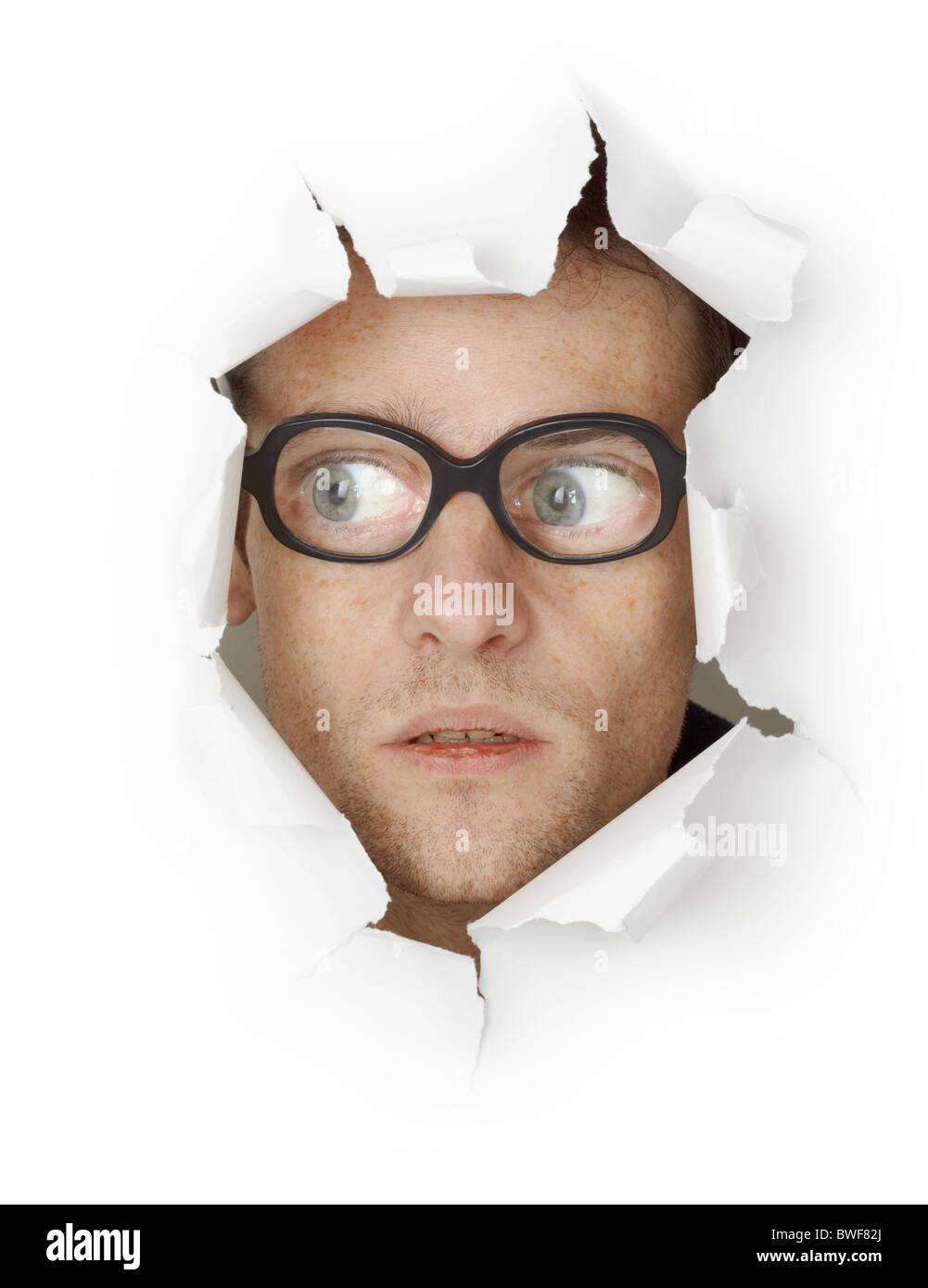 Funny man in an old-fashioned glasses looking out of the hole isolated on white background Stock Photo