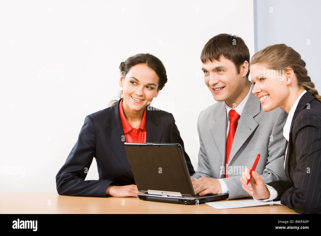 Photo of friendly business people sitting at table and looking forward  during working meeting Stock Photo - Alamy
