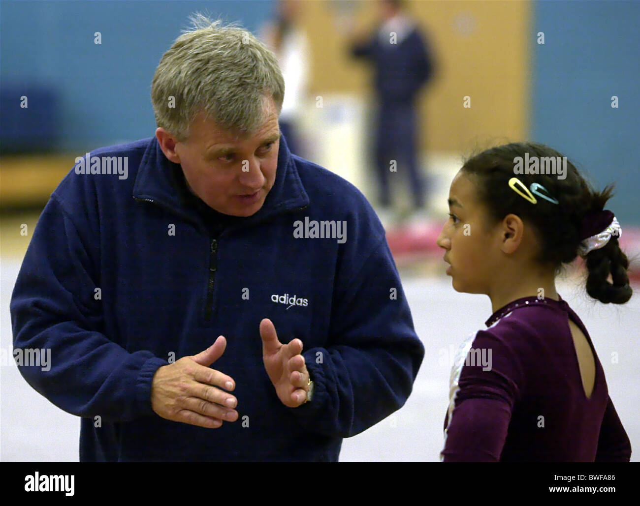 A gymnastics coach gives instructions to a young gymnast Stock Photo