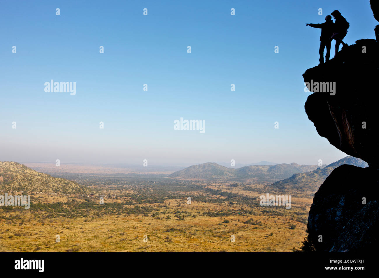 Climbers standing on a cliff looking out onto an open landscape Stock Photo