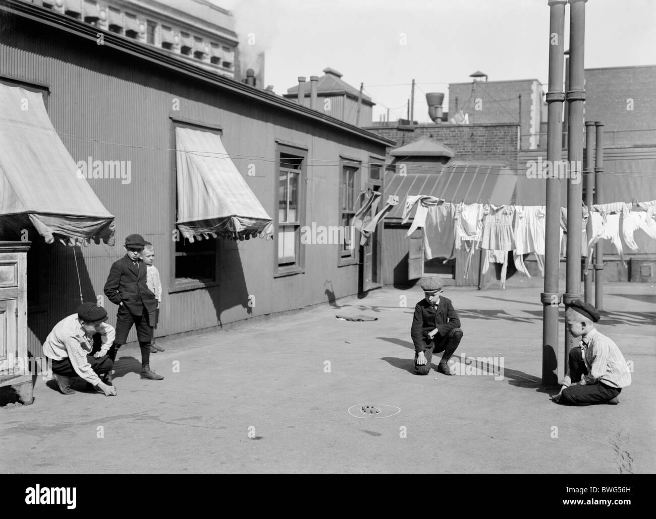 Vintage photo c1910 of young boys playing marbles on the roof of a "skyscraper" apartment building in New York City. Stock Photo