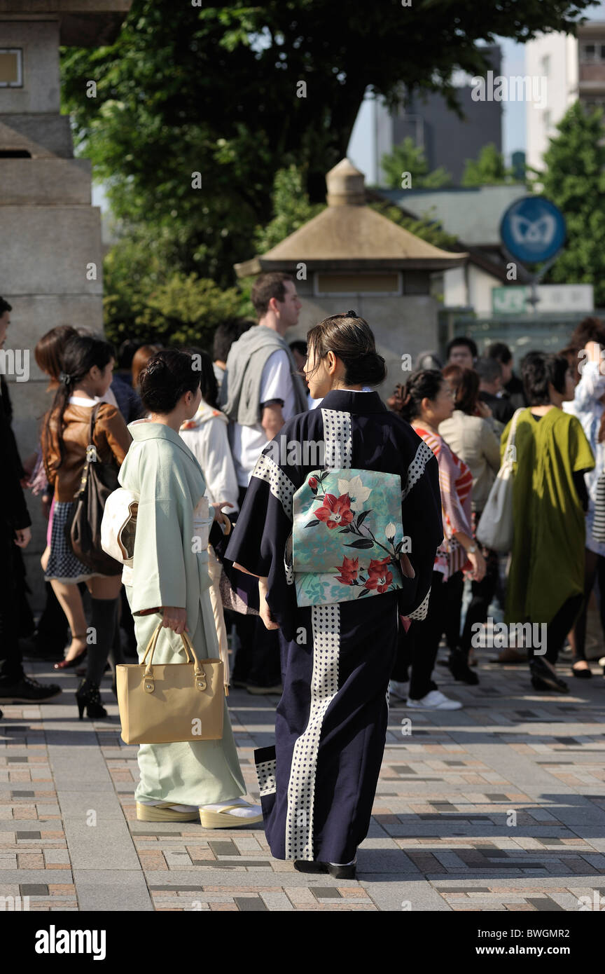 Two young Japanese women in traditional Geisha-like outfits on crowded Jingu bridge, Harajuku, Tokyo, Japan Stock Photo