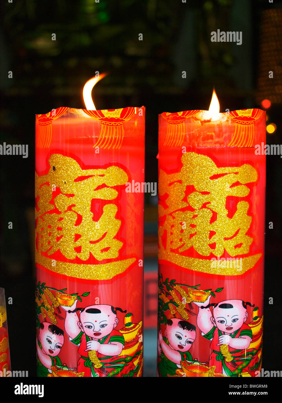 Two brightly decorated Chinese candles burn in a temple in Shanghai, where preys are being said