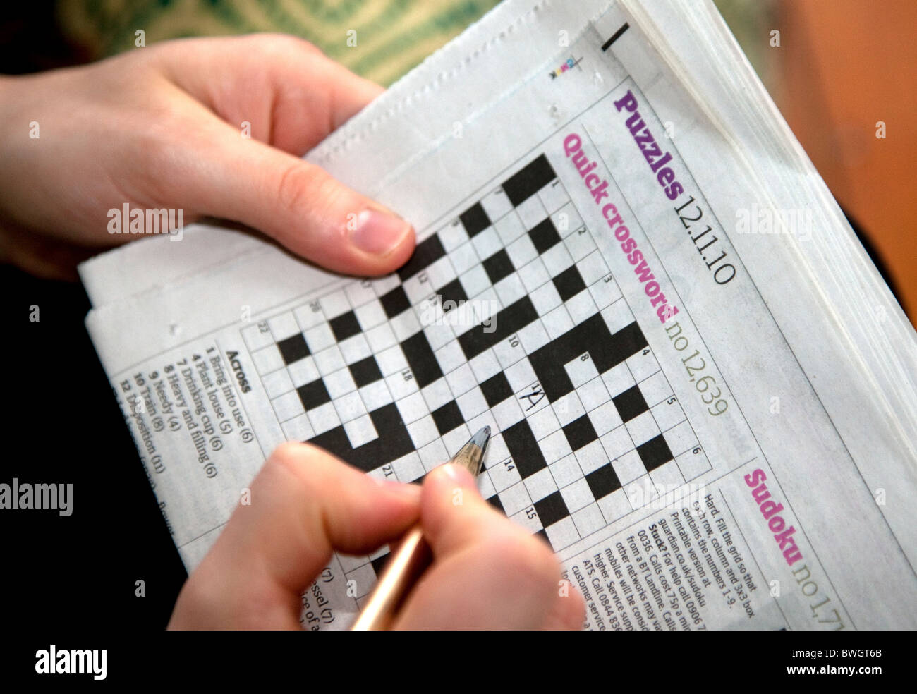 Solving a quick newspaper crossword, London Stock Photo - Alamy
