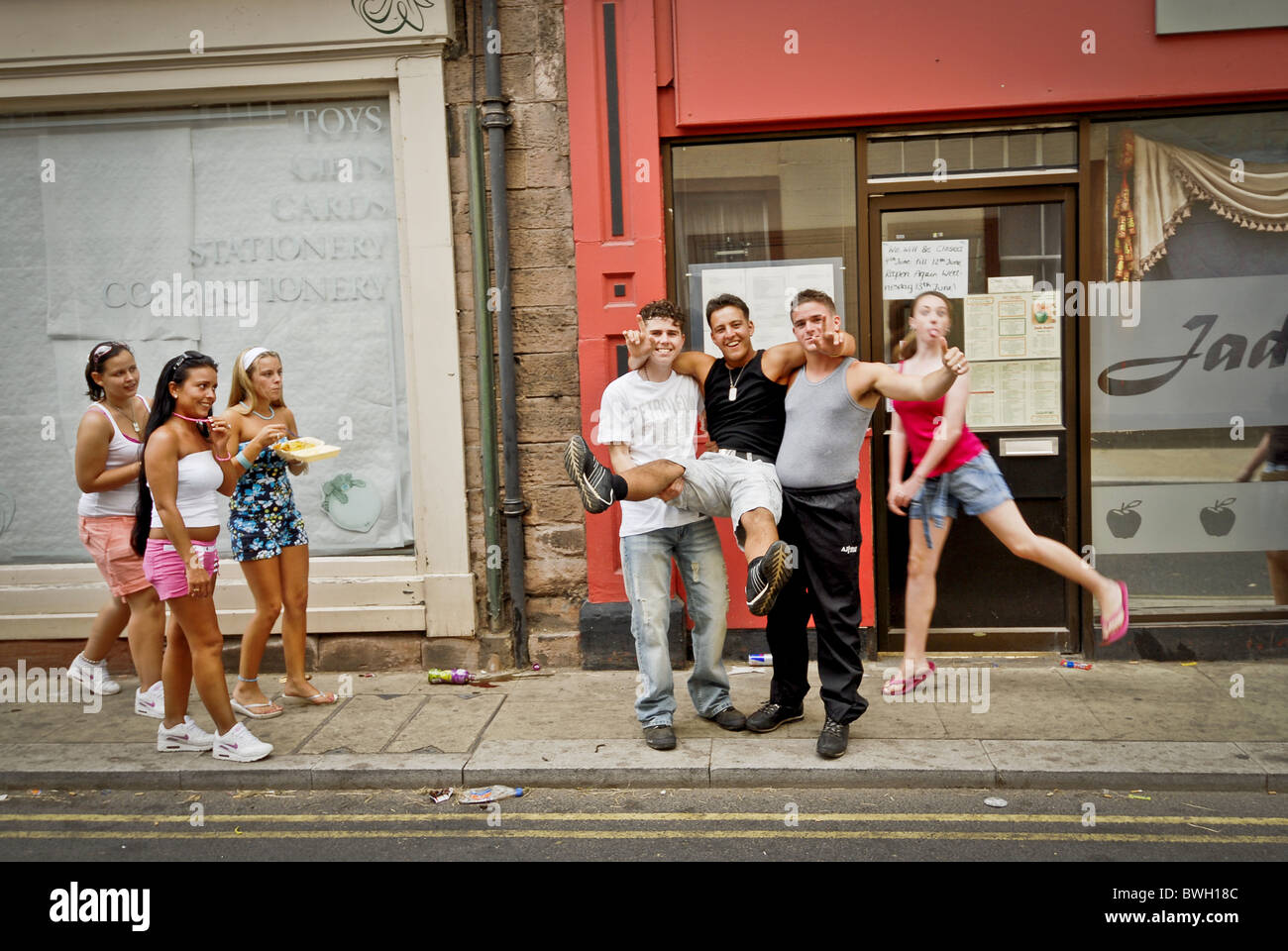 Group of male and female youths show off on high street. Stock Photo