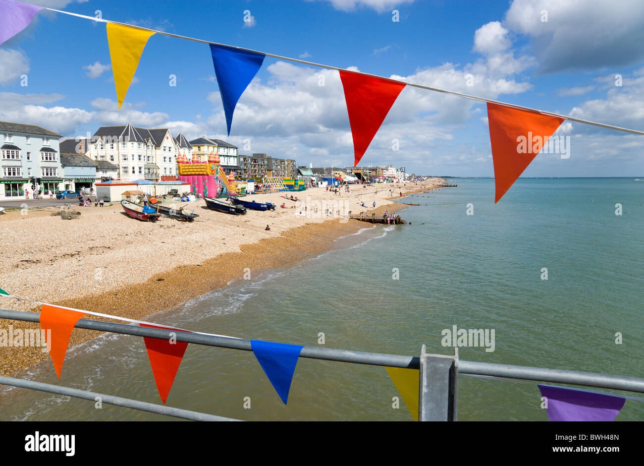England West Sussex Bognor Regis The pebble shingle beach and seafront with tourists seen through colourful flags on pier Stock Photo
