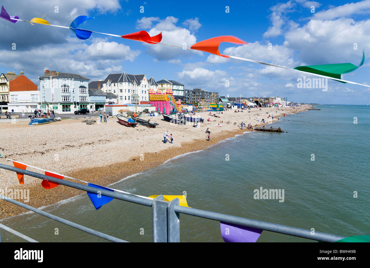 England West Sussex Bognor Regis The pebble shingle beach and seafront with tourists seen through colourful flags on pier Stock Photo