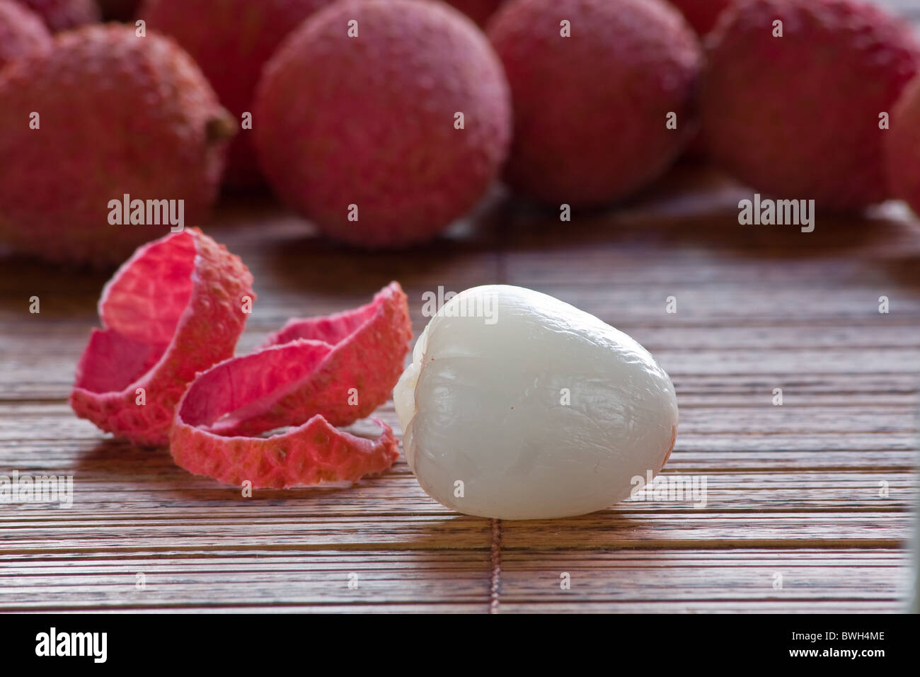 Whole and peeled lychee on bamboo mat Stock Photo