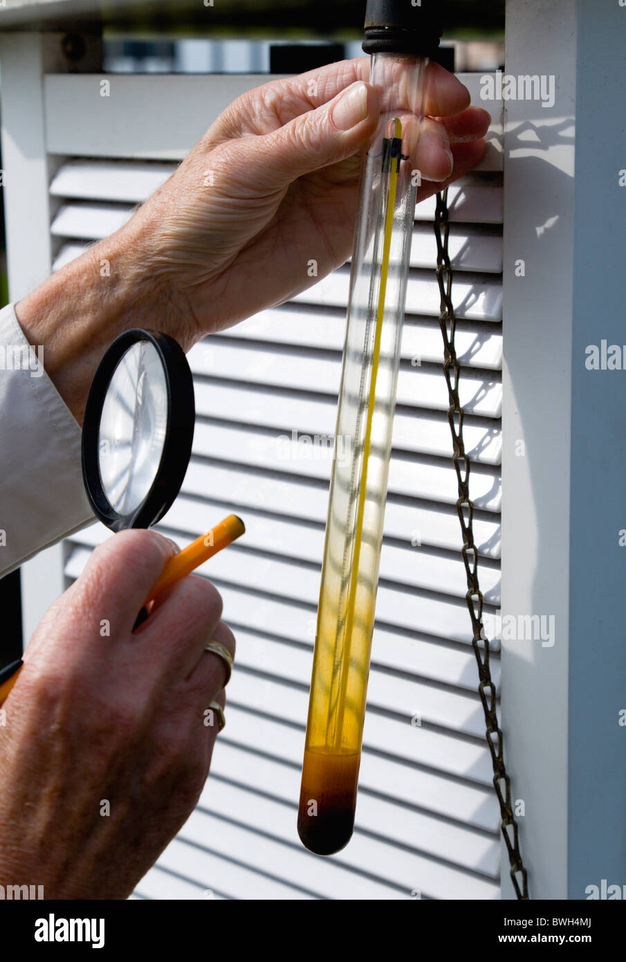 Climate Weather Station Measurement observer using magnifying glass to read thermometer that records underground temperature Stock Photo