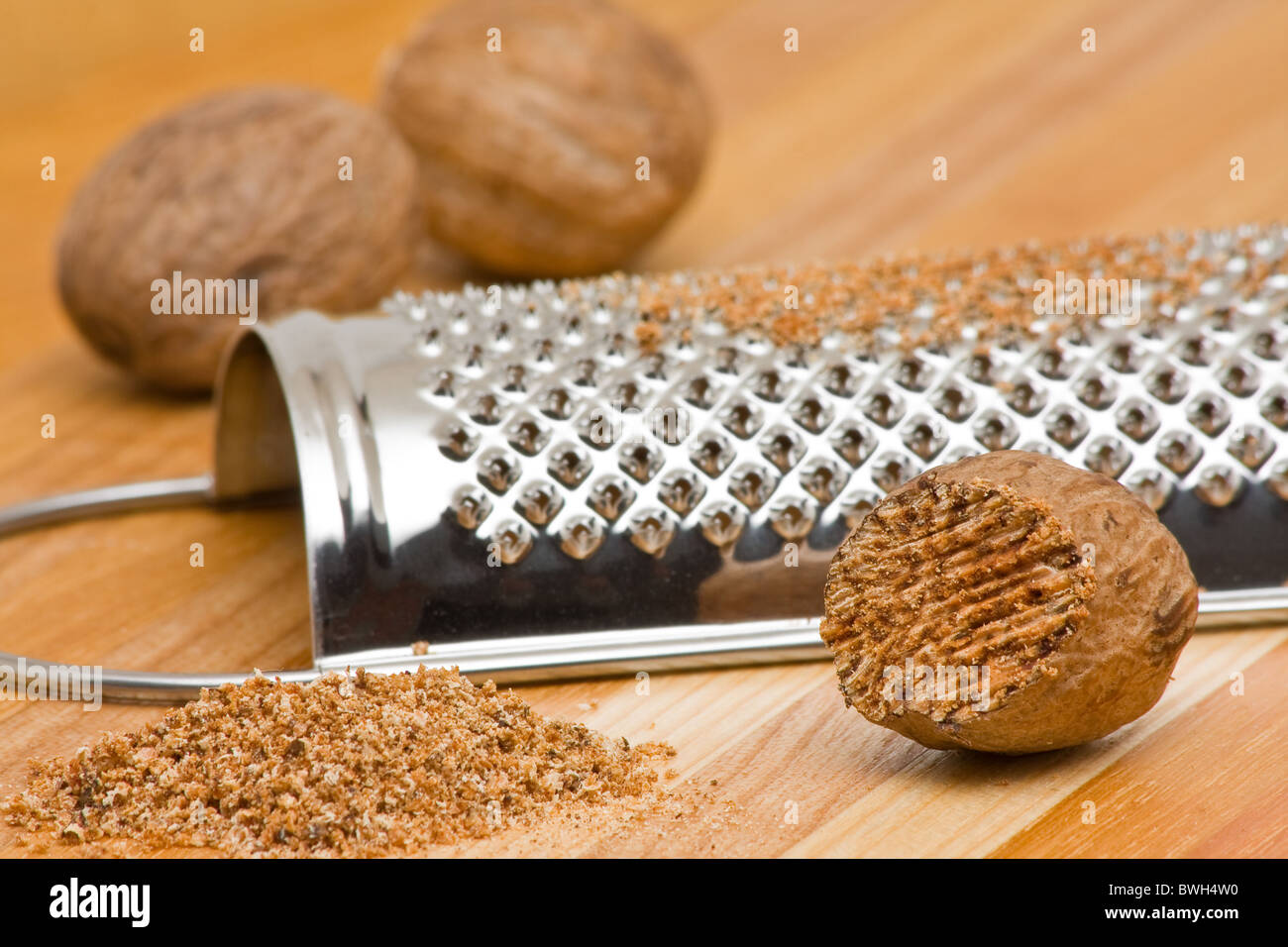 Whole and grind nutmeg with grinder over wood background Stock Photo
