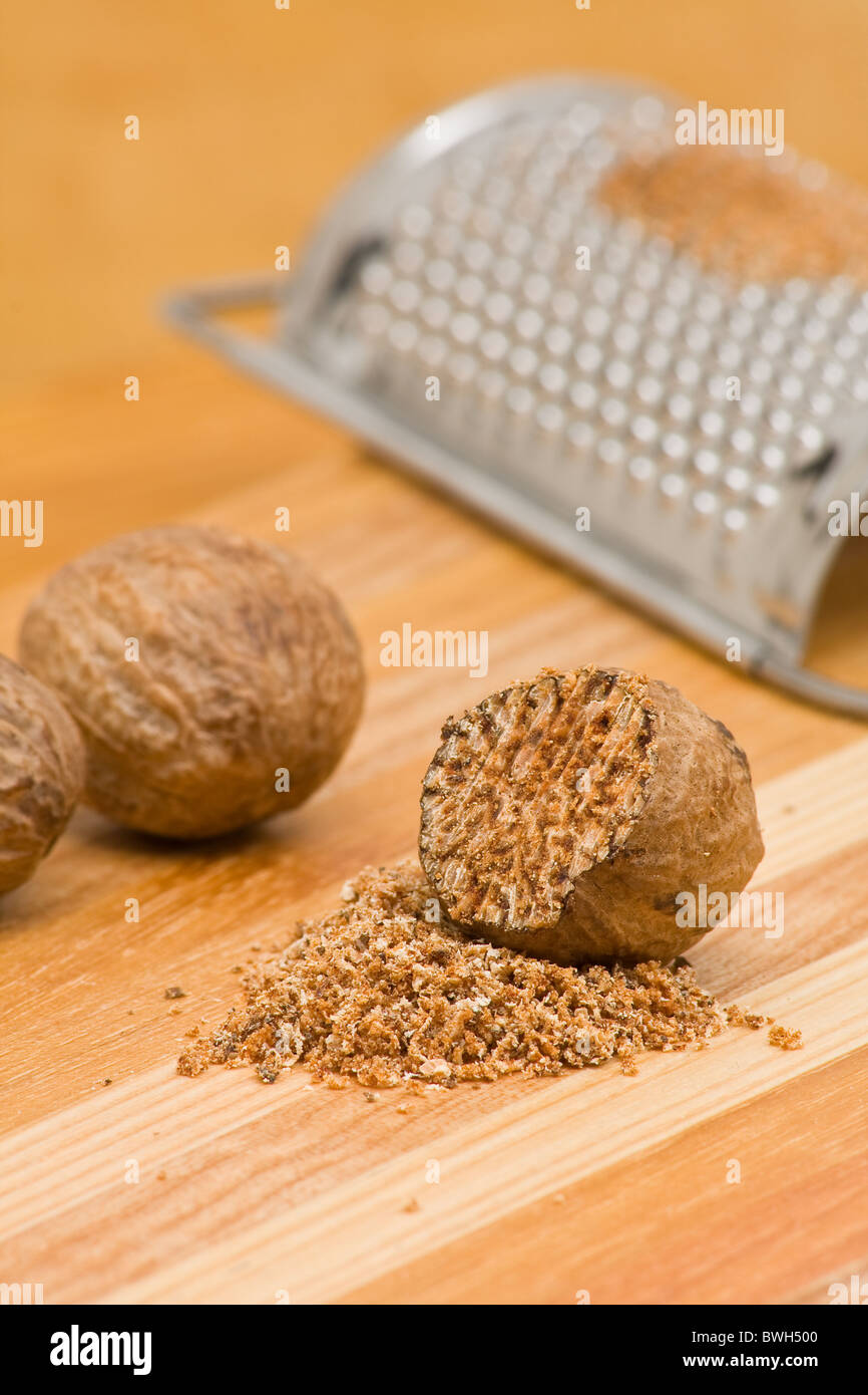 Whole and grind nutmeg with grinder over wood background Stock Photo