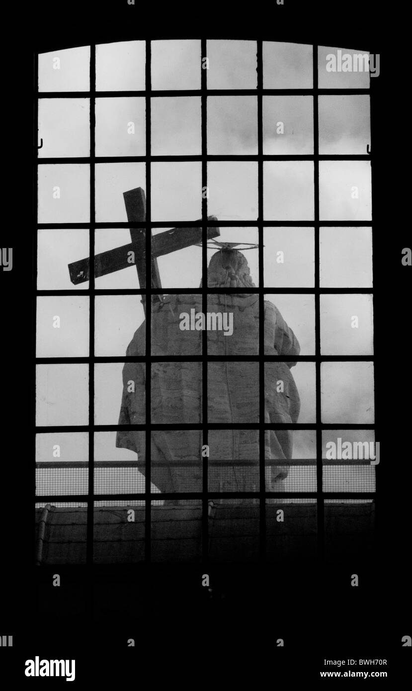 A black and white image of a statue of Jesus, holding the cross at the ...