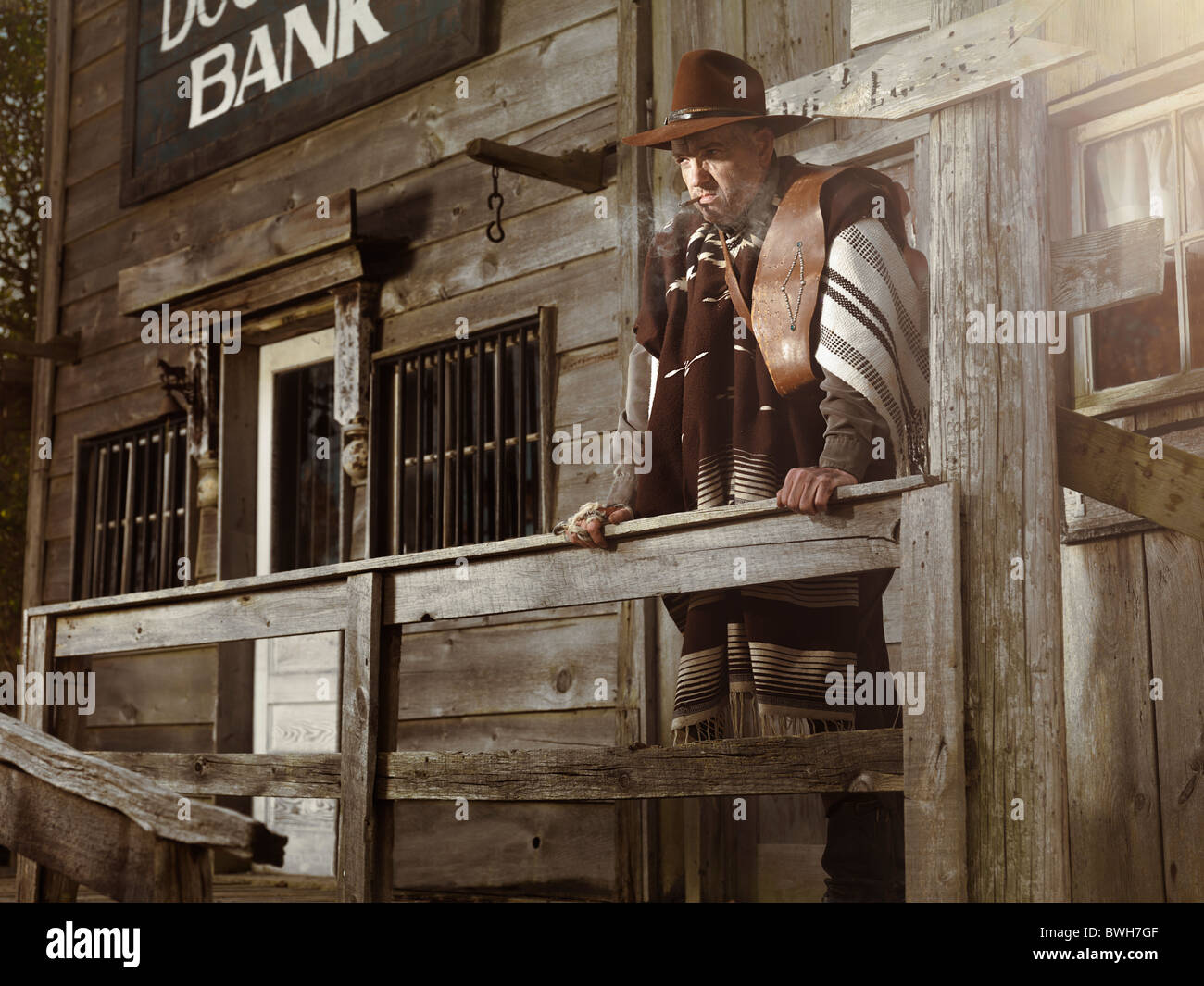 Cowboy with a cigar in his mouth standing in outside of a bank building Stock Photo