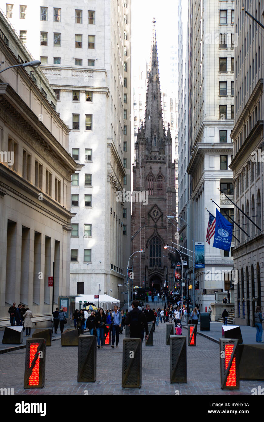 USA New York NYC Manhattan Gothic Trinity Church with people walking in Wall Street by security barriers Stock Photo