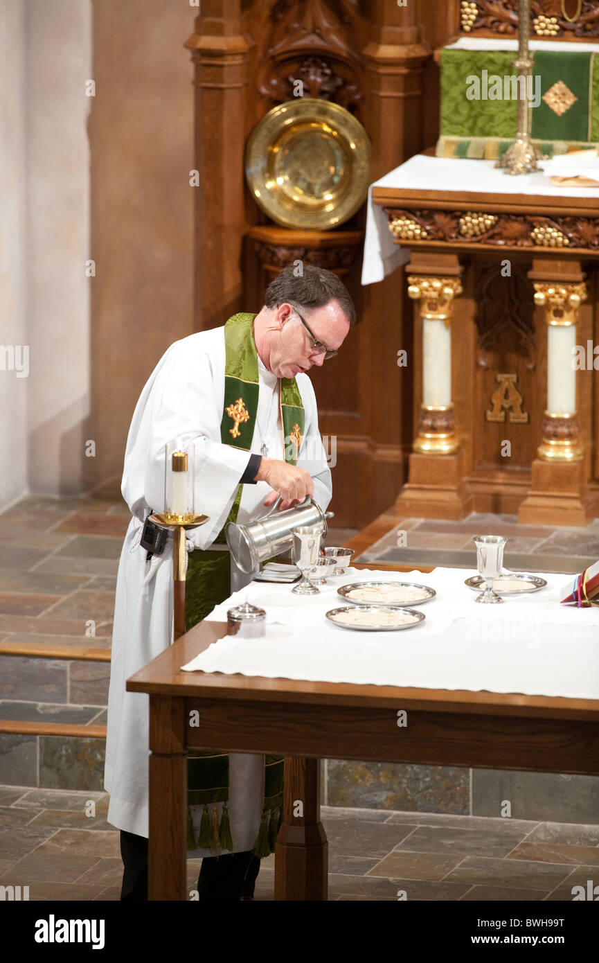 Anglo male presiding minister pours wine into communion cup before congregational communion during service at Lutheran church Stock Photo