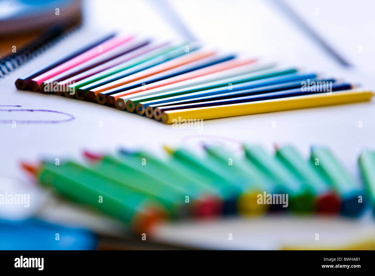 Colored pencils and crayons on top of paper art books selective focus Stock Photo
