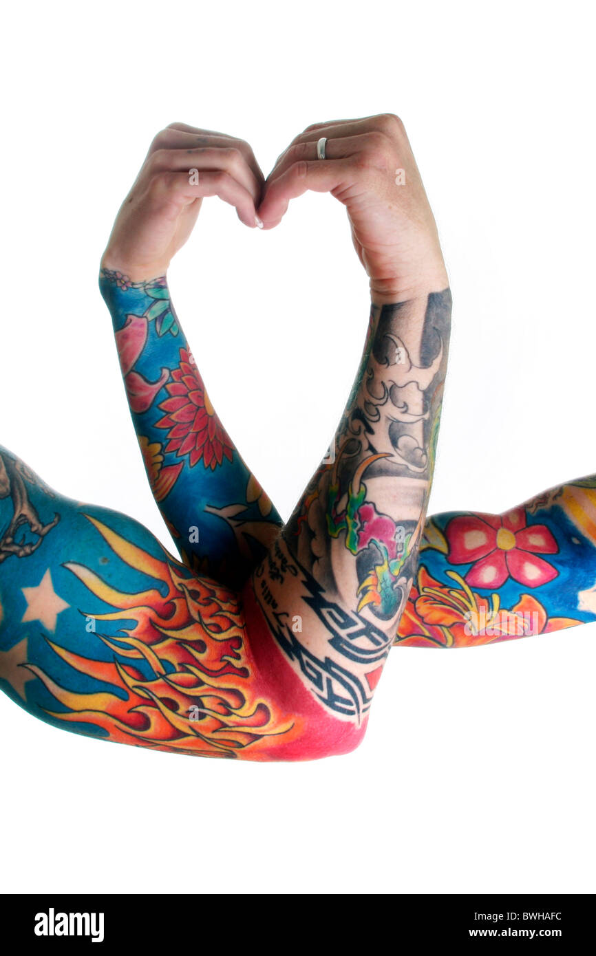 Couple in love make heart shape with their tattooed arms Stock Photo