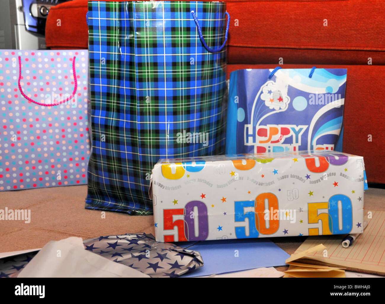 opened and unopened 50th birthday presents lying on the carpet. Stock Photo