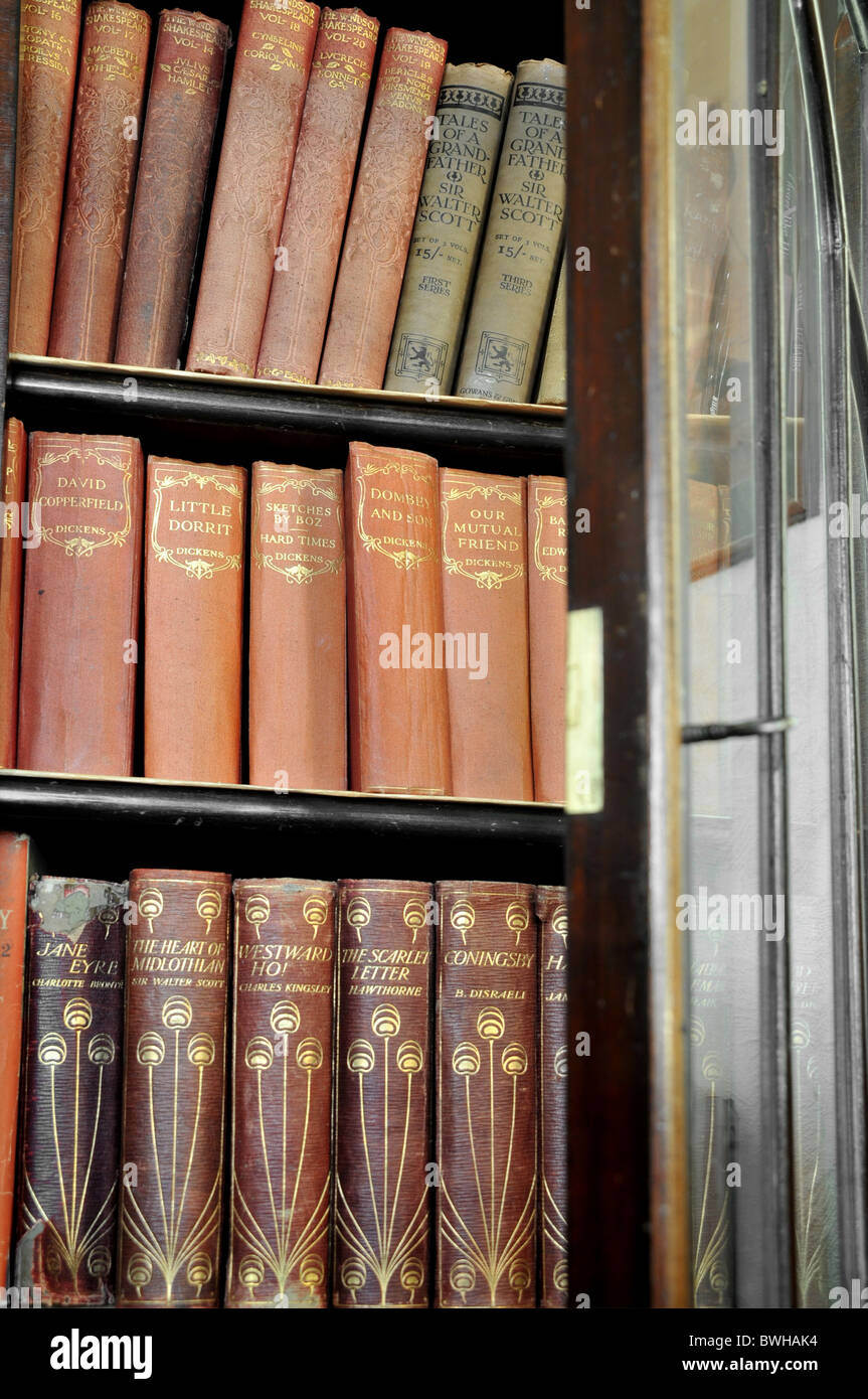 An opened  glassed door bookcase with old editions of classic novels. Stock Photo