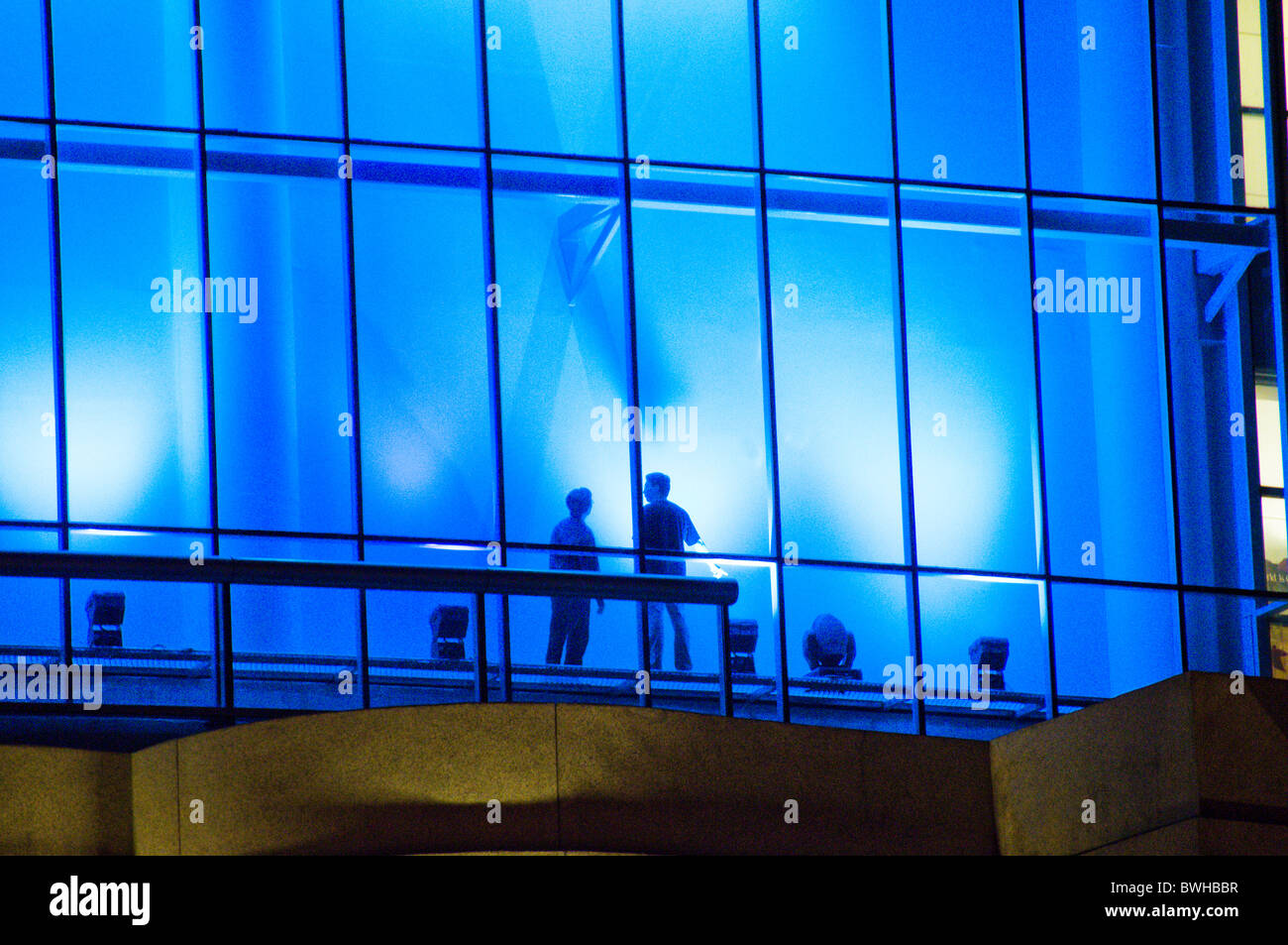 Two men standing in front of blue window on exterior of mall in Singapore Stock Photo