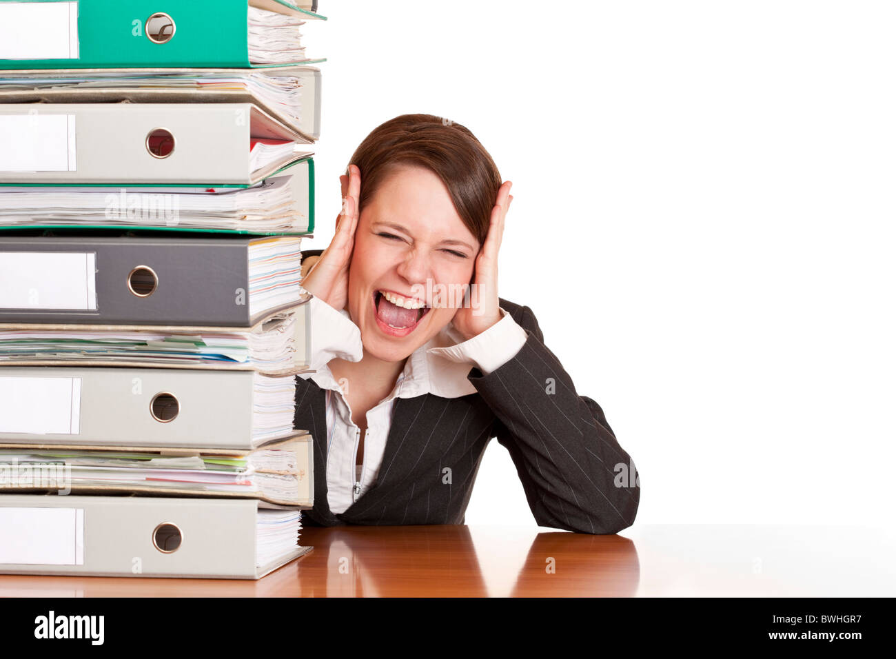 Frustrated business woman cries in office behind behind a folder stack. Isolated on white background. Stock Photo