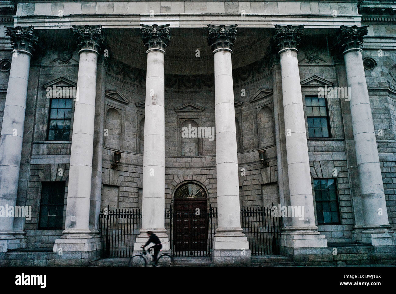 A cyclist cycles past the Four Courts on a wet wintry day Dublin Ireland Stock Photo