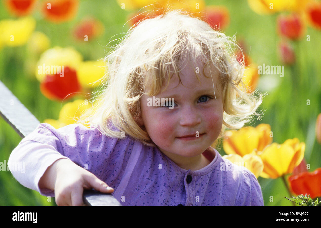 girls outside blond locks child toddler infant portrait nature flowers tulips Stock Photo
