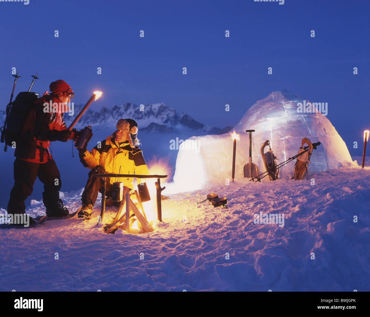 Couple fire campfire torches snow shoes snow shoe walking igloo illuminated Pizol mountains Alps winter sn Stock Photo