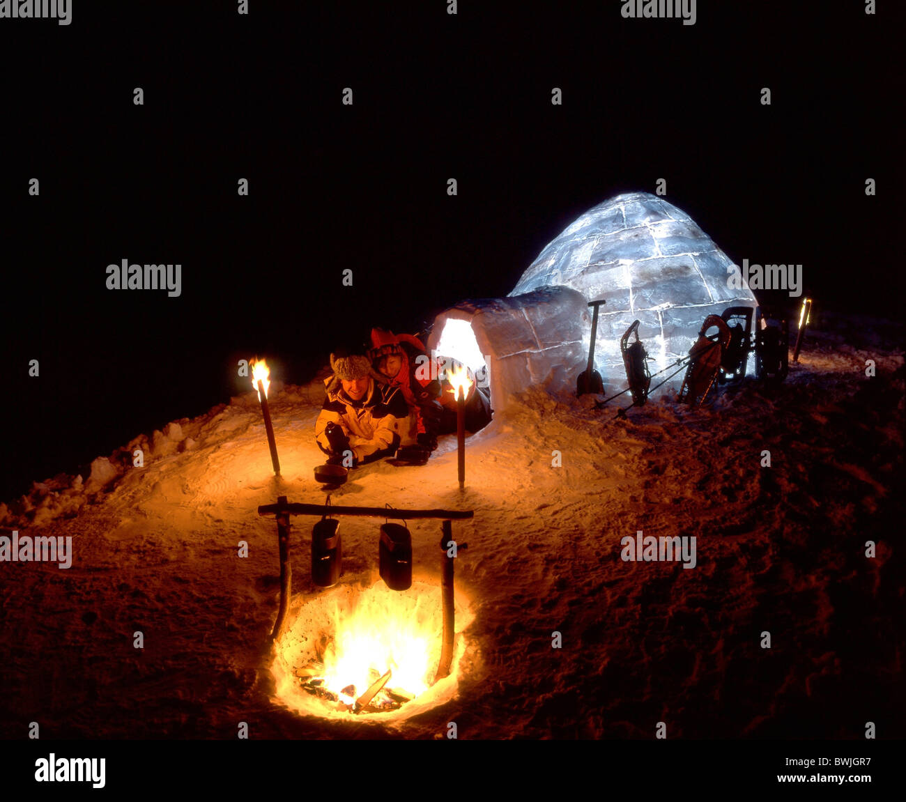 Couple at night night fire campfire torches snow shoes snow shoe walking igloo illuminated Pizol mountains Stock Photo