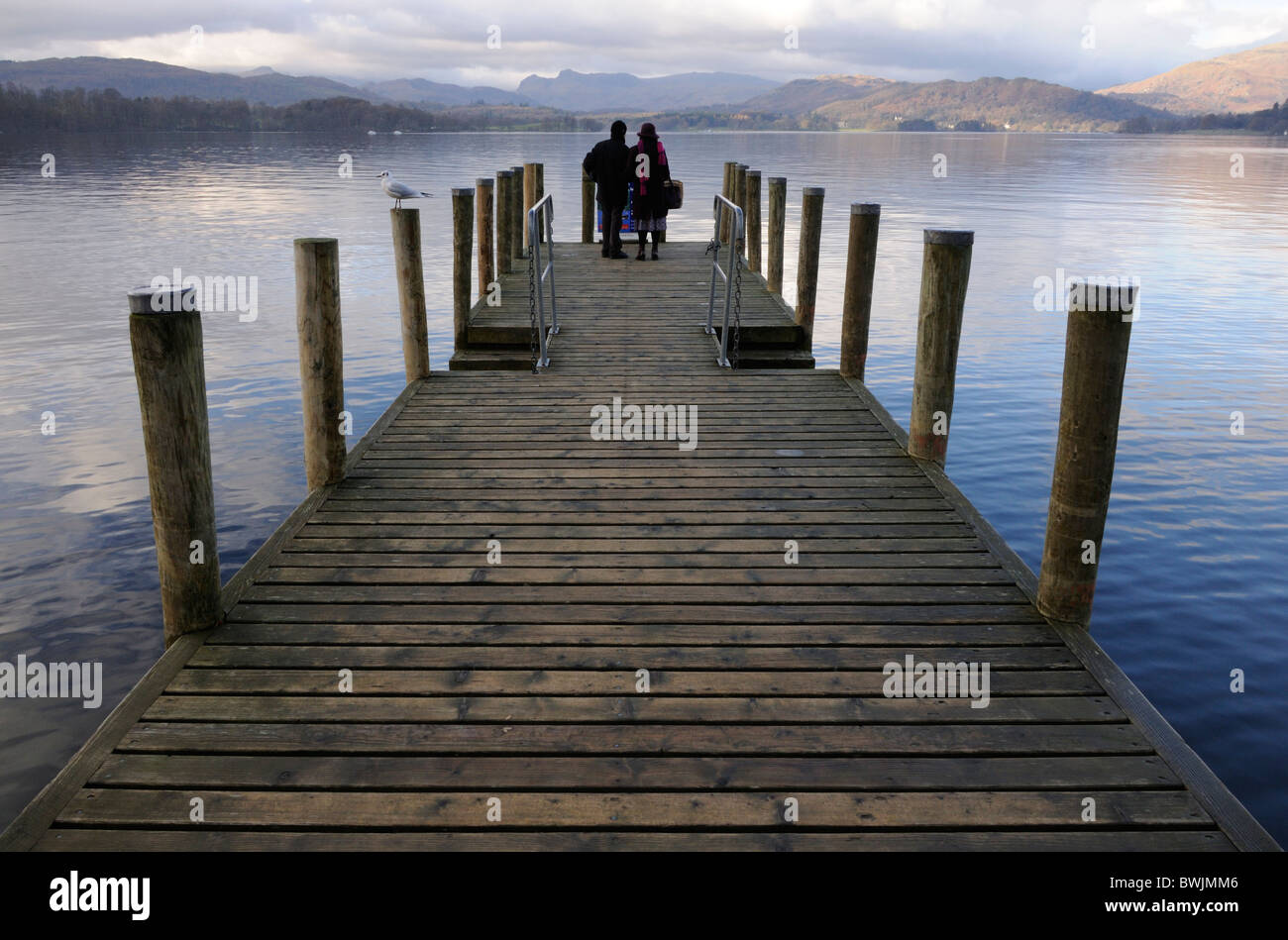 A couple standing at the end of a jetty on Lake Windermere, Lake District Stock Photo