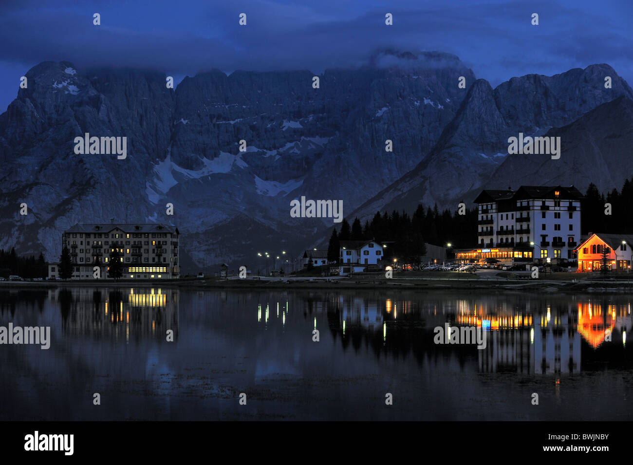 The mountain range Gruppo del Sorapis and hotels at night along lake Lago di Misurina in Auronzo di Cadore, Dolomites, Italy Stock Photo