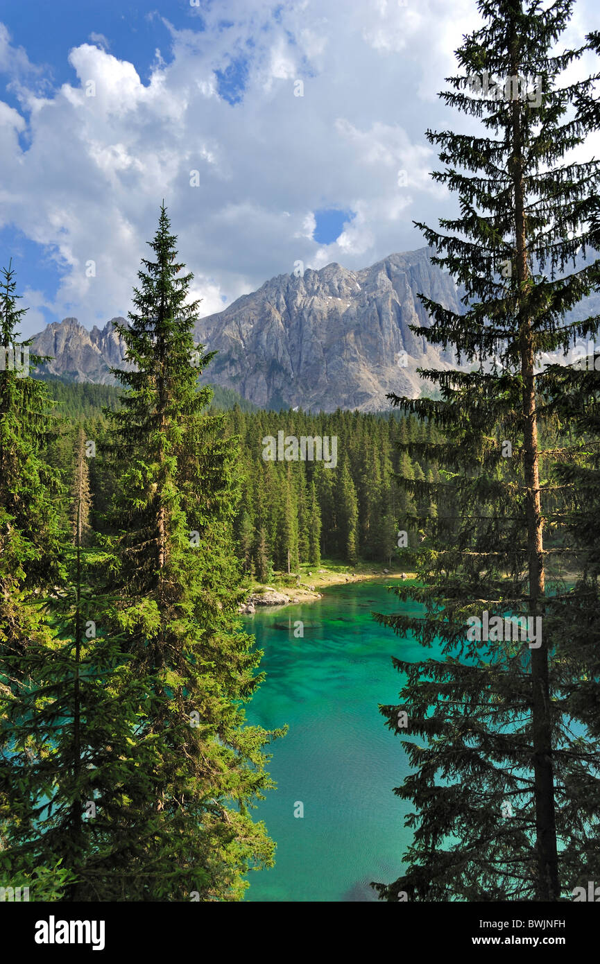 The lake Lago di Carezza / Karersee surrounded by mountain peaks and pine forest in the Dolomites, Italy Stock Photo