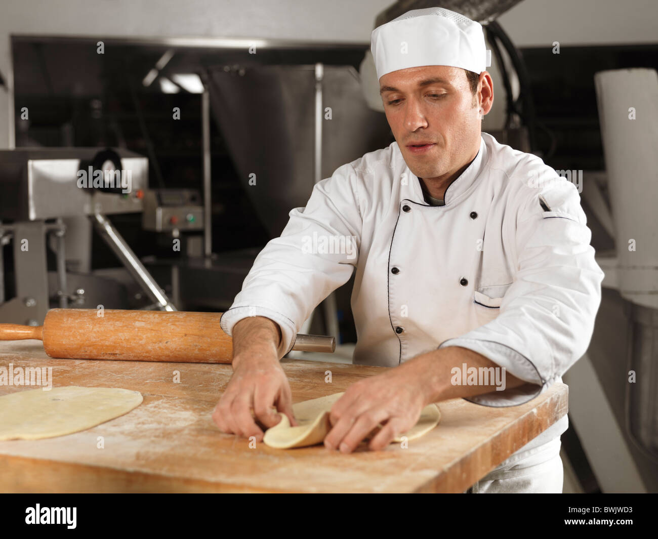 Baker rolling out dough in a bakery Stock Photo