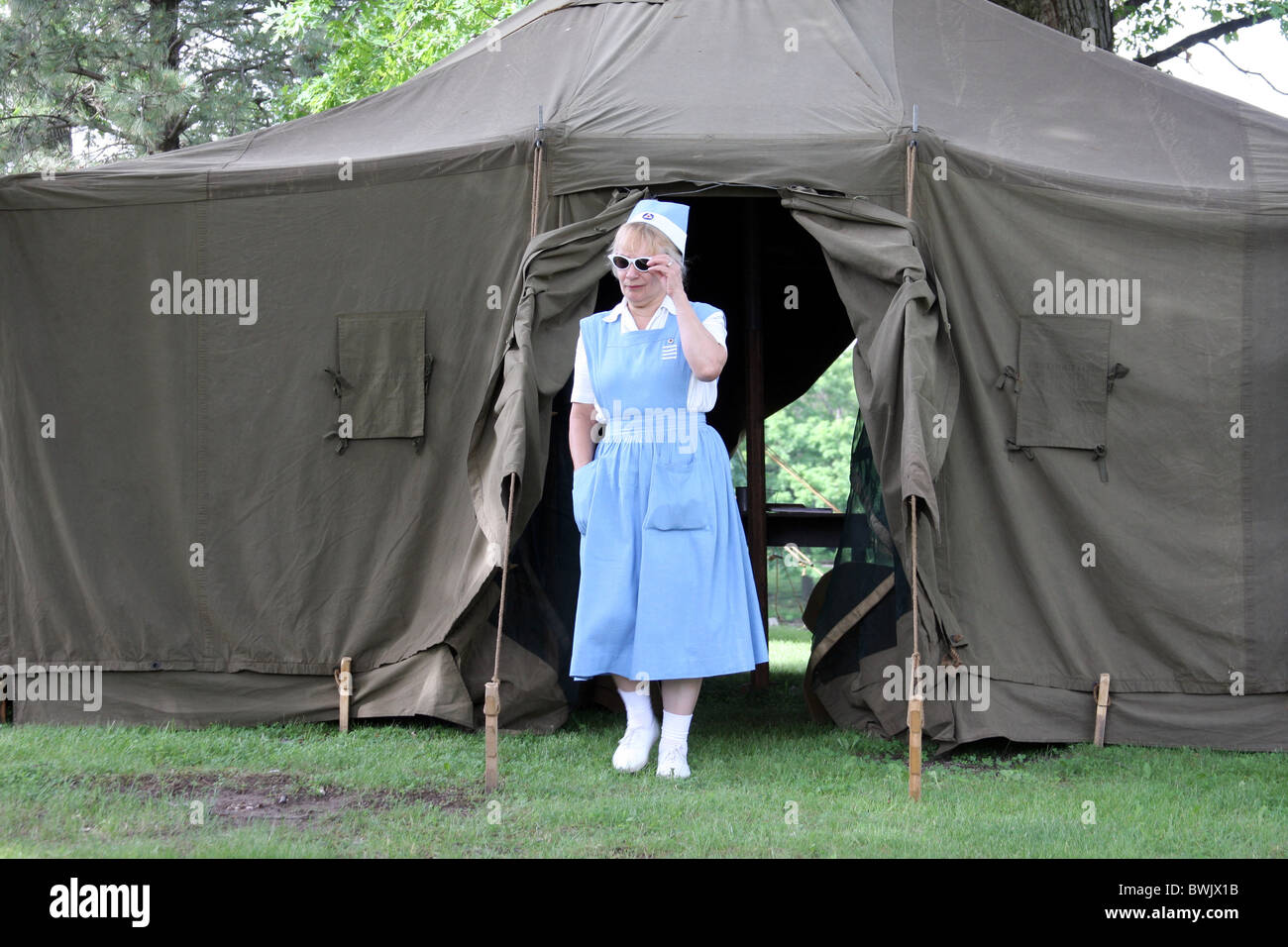 A World War II WWII nurse coming out of a tent in camp 1945 red cross medical help hospital doctor Stock Photo