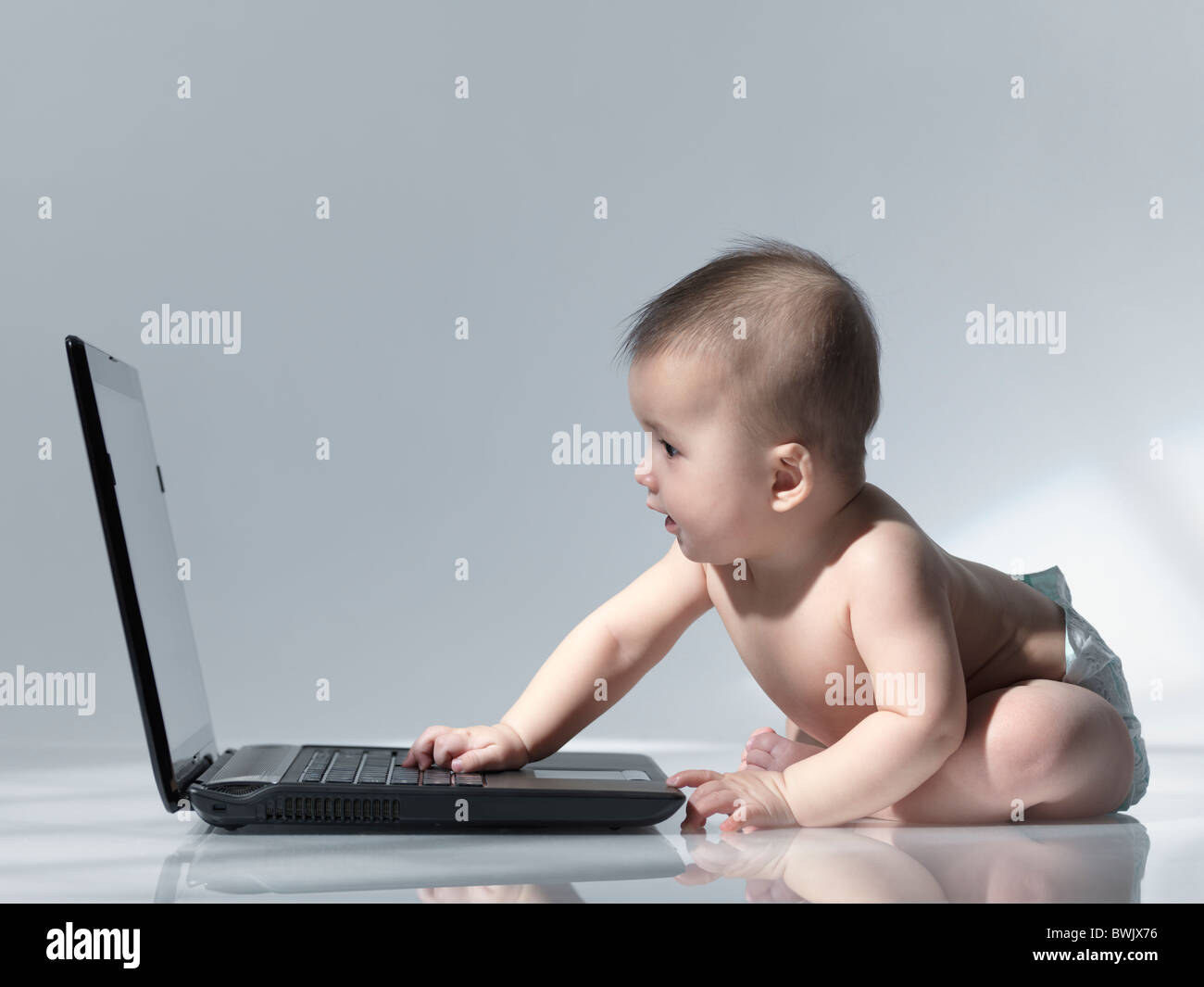 Six month old baby sitting in front of a laptop computer Stock Photo