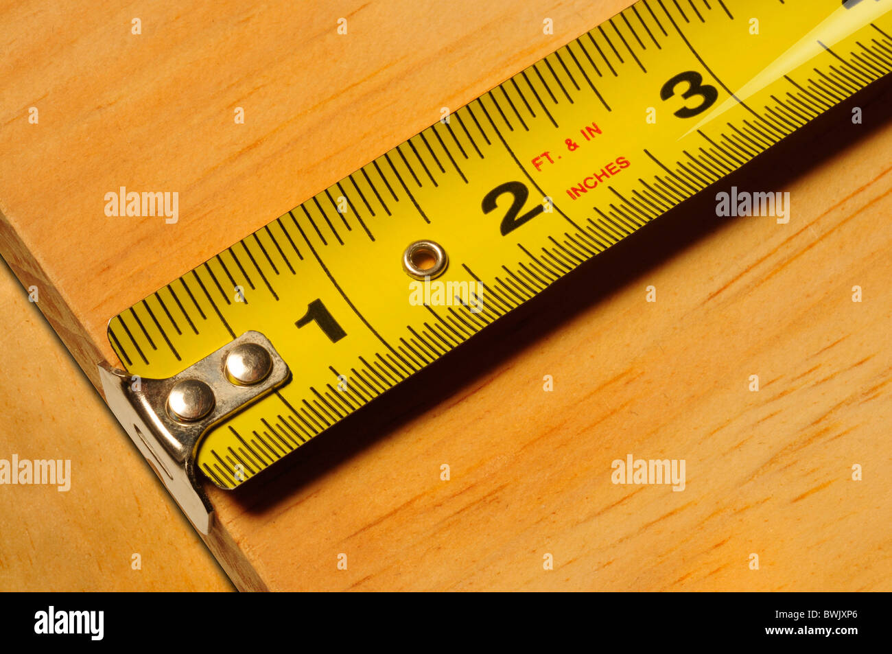 Close-up of a yellow tape measure measuring a piece of wood Stock Photo
