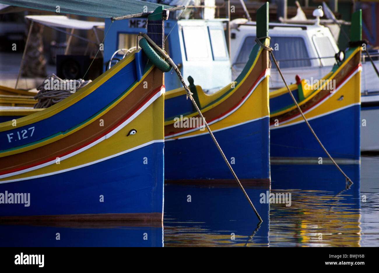 Malta. Brightly painted blue and yellow fishing boats showing the traditional eye of Horus in Marsaxlokk Harbour. O Stock Photo