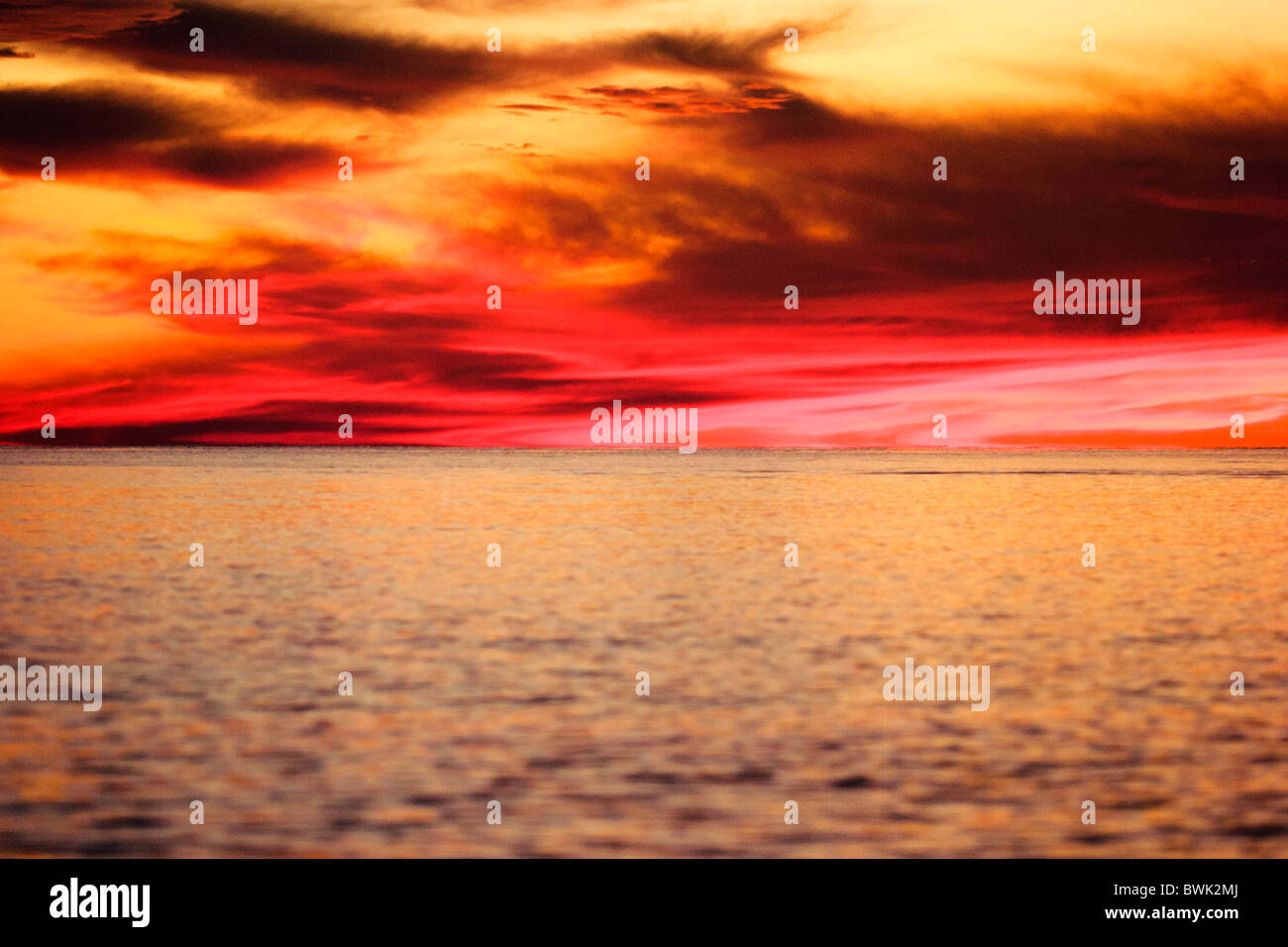 Dramatic sunset clouds over calm water. Stock Photo