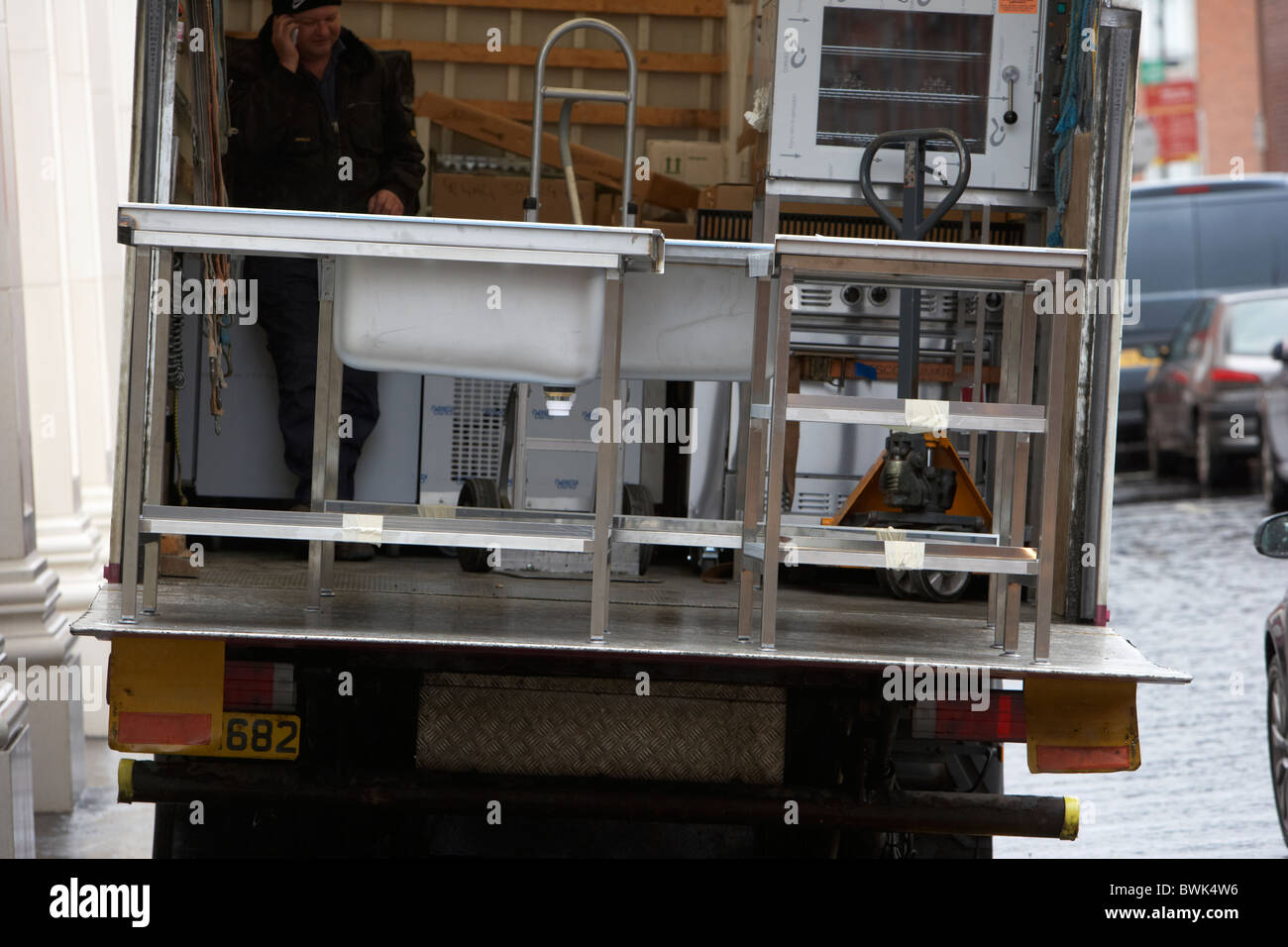 man delivering restaurant commercial kitchen equipment in a tail lift van in the uk Stock Photo