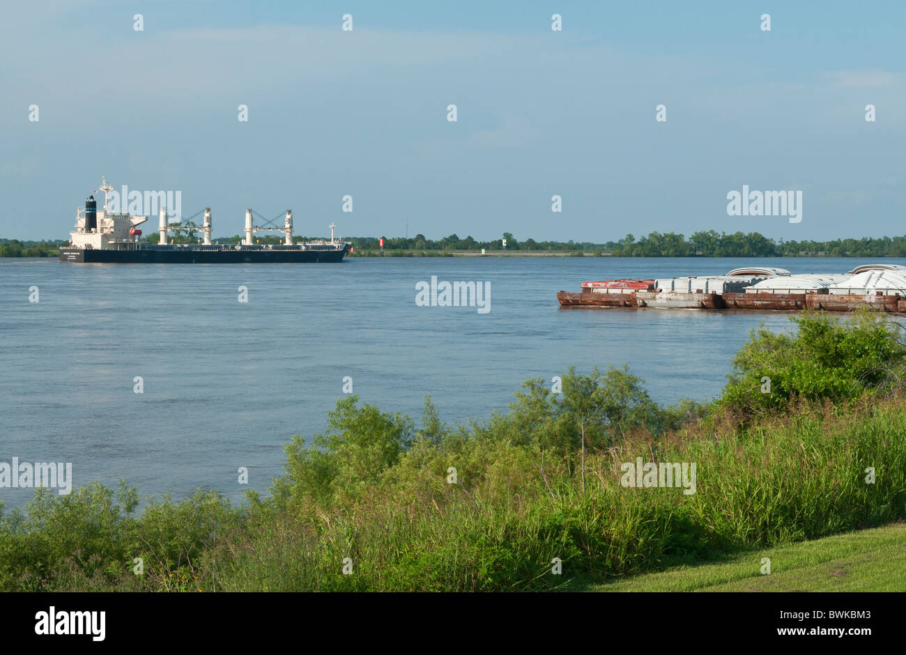 view from levee of barges and ocean going freighter ship on Mississippi River near Vacherie, Louisiana Stock Photo