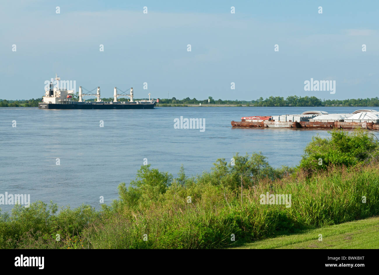 view from levee of barges and ocean going freighter ship on Mississippi River near Vacherie, Louisiana Stock Photo