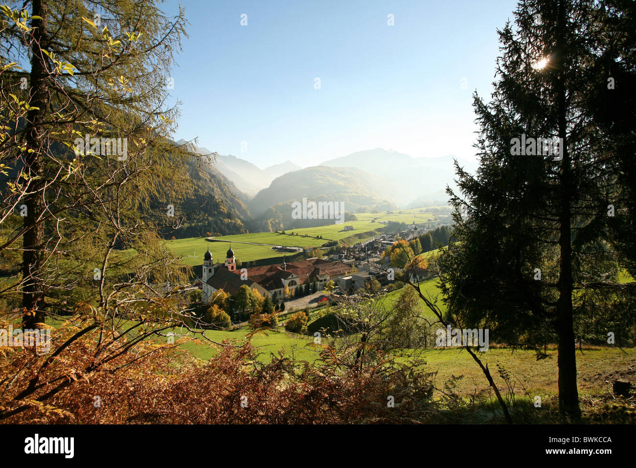 cloister Disentis village overview autumn scenery landscape larches mountains Alps smoke mountains Grisons Stock Photo