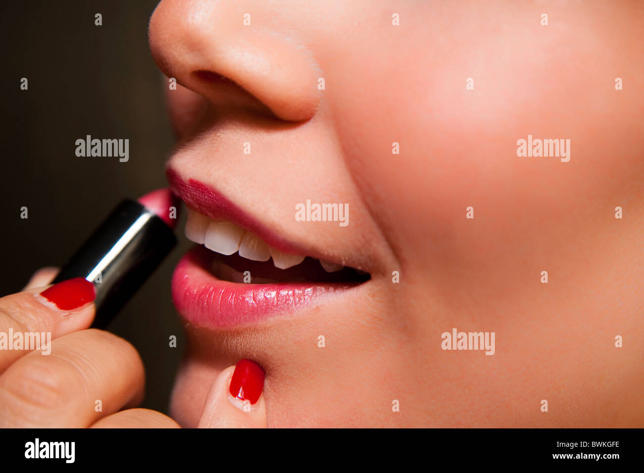 Woman putting on red lipstick Stock Photo