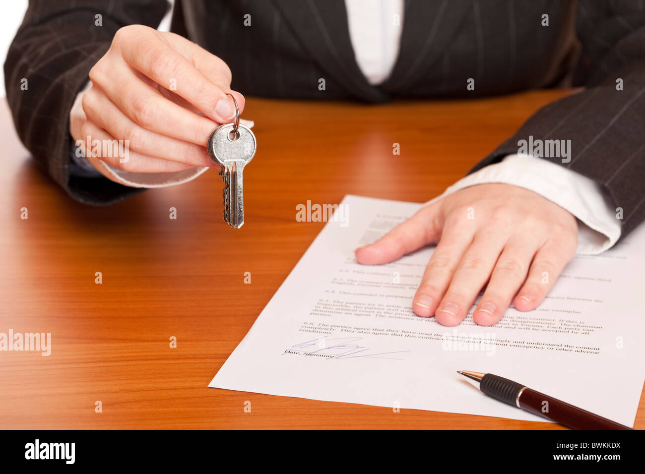 Business woman holds key and contract in hands. Isolated on white background. Stock Photo