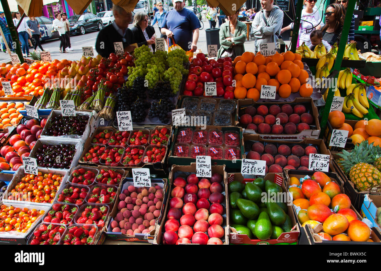 Selection of fresh fruits and vegetables and customers shopping at at