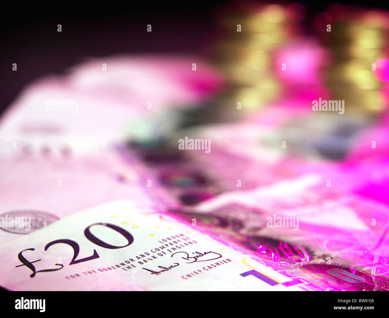 UK pound sterling with a twenty pound note in foreground lit with dramatic lighting Stock Photo