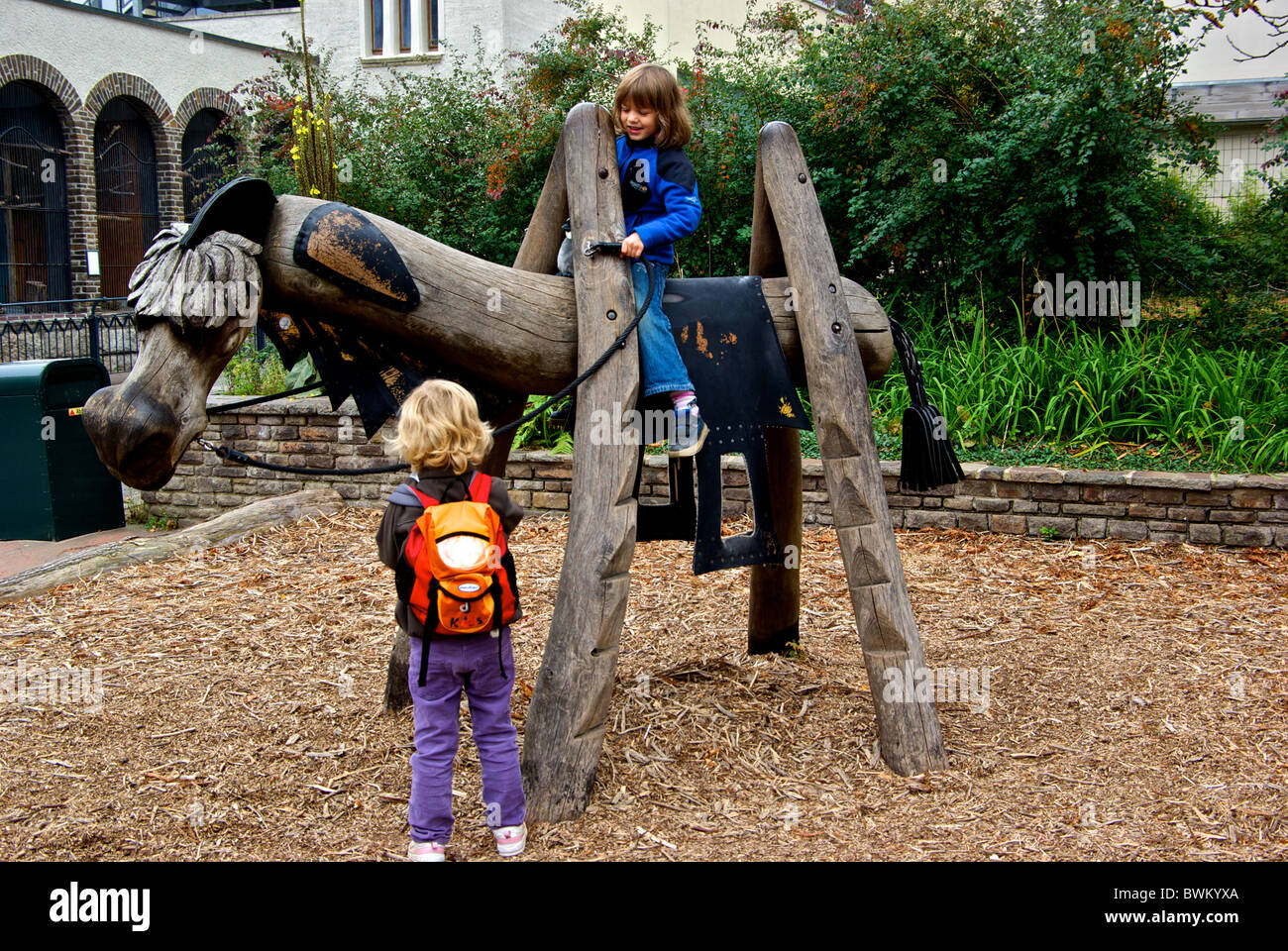 Children playing a stylized wooden horse at Leipzig Zoological Gardens Stock Photo