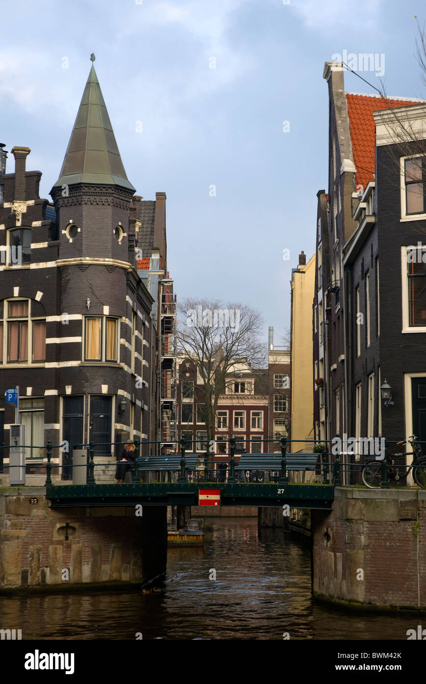 Canalside scene in Amsterdam, Holland, with pointed tower and red tiled buildings. Stock Photo
